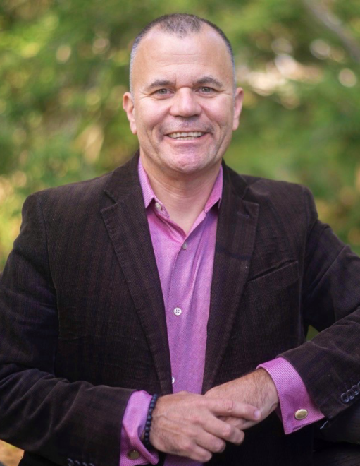 Headshot of Kevin N. Kovalycsik, UAF CTC dean candidate, smiling and wearing a black blazer over a lilac shirt. 